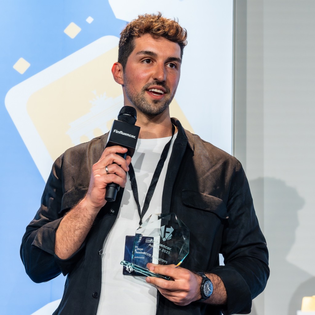 Simon Schöbel auf der Bühne mit Mikrofon und Finfluencer Award